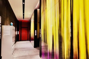 A corridor with a red door at the end, a vending machine, and a wall with vertical lines. - Queen Suites Tropicana The Residence by KLCC (Kuala Lumpur)