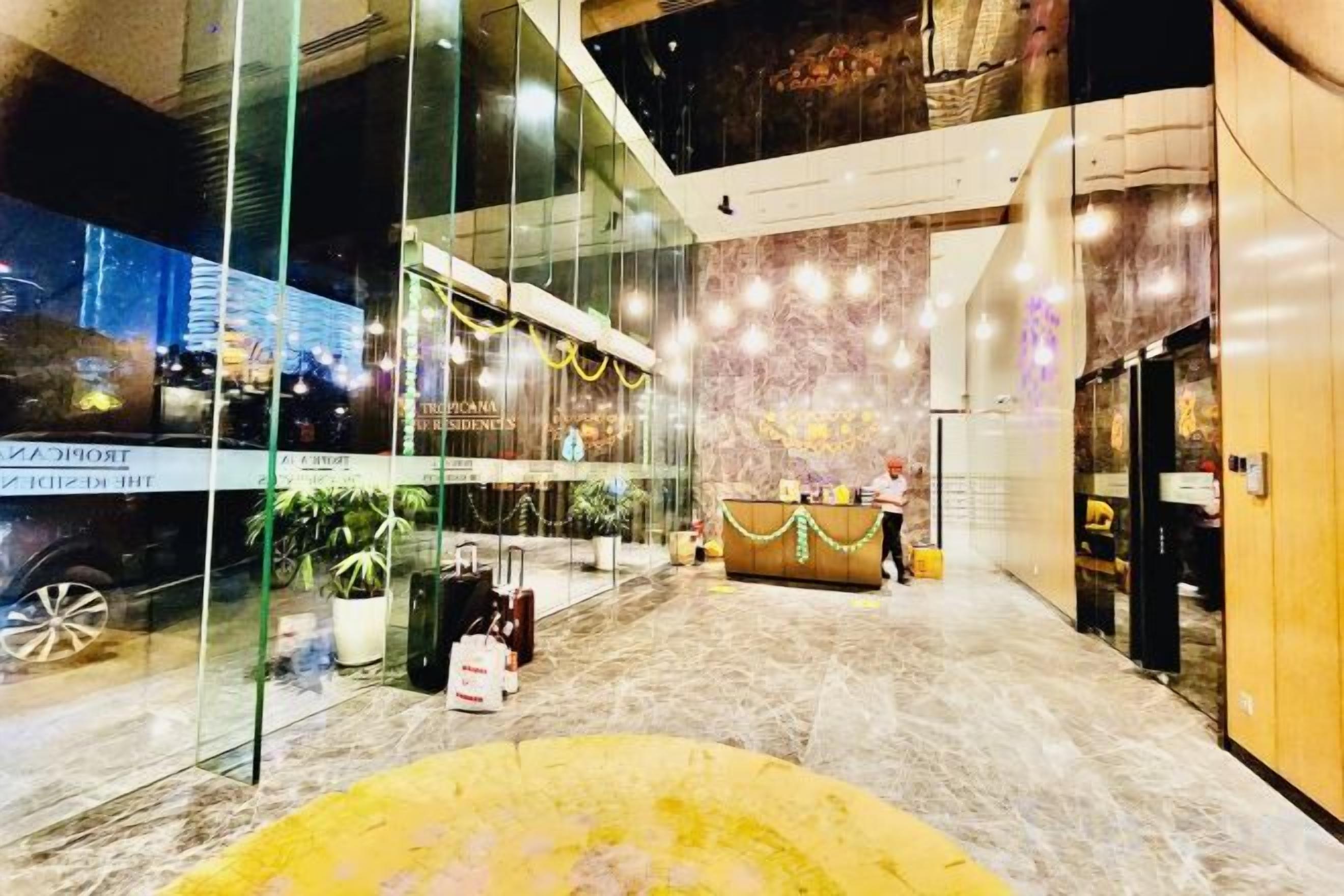 Un hall d’hôtel avec un comptoir d’accueil, des murs en verre et une vue sur le paysage urbain.