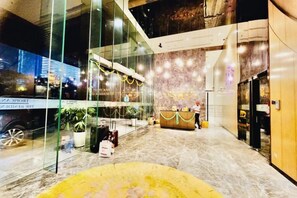 A hotel lobby with a reception desk, glass walls, and a view of the cityscape. - Queen Suites Tropicana The Residence by KLCC (Kuala Lumpur)