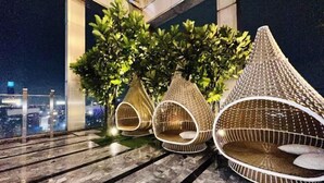 Un balcon avec trois chaises en osier et une plante en pot.