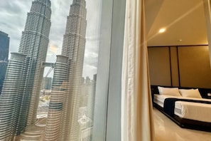 A hotel room with a bed, a view of the Burj Khalifa, and a window with curtains. - Queen Suites Tropicana The Residence by KLCC (Kuala Lumpur)