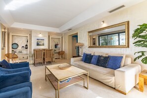 A modern living room with a sofa, coffee table, and dining area.
