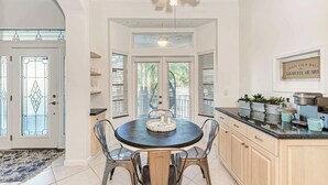A kitchen with a round table, chairs, a ceiling fan, and a coffee maker. - Cottage on Lido Key - One block to Beach, Pool (Sarasota)