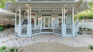 A two-story house with a covered porch, white railings, and a brick pathway leading to the entrance. - Cottage on Lido Key - One block to Beach, Pool (Sarasota)