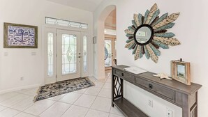 A hallway with a decorative mirror, a rug, and a console table with a picture frame and a shell. - Cottage on Lido Key - One block to Beach, Pool (Sarasota)