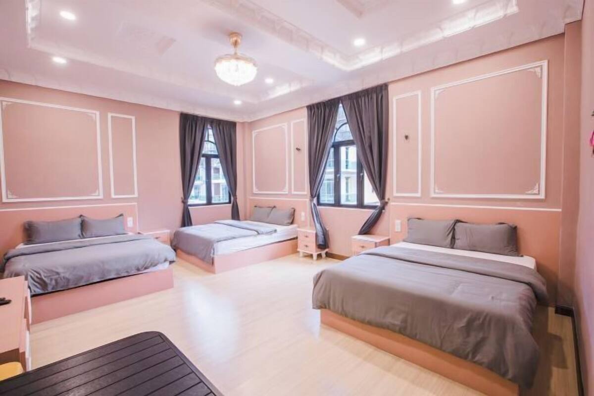 A bedroom with three beds, a desk, and a chair.