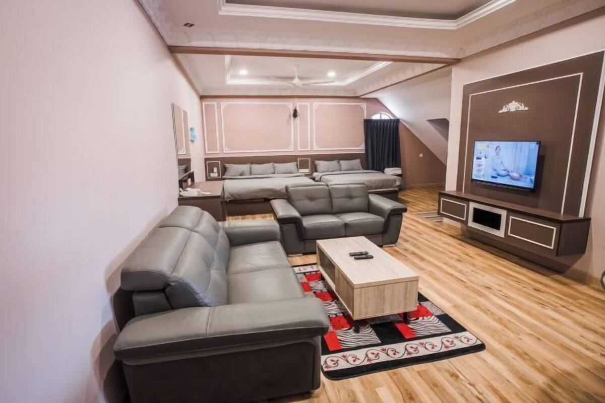 A modern living room with a sectional sofa, a coffee table, and a flat-screen TV mounted on the wall.
