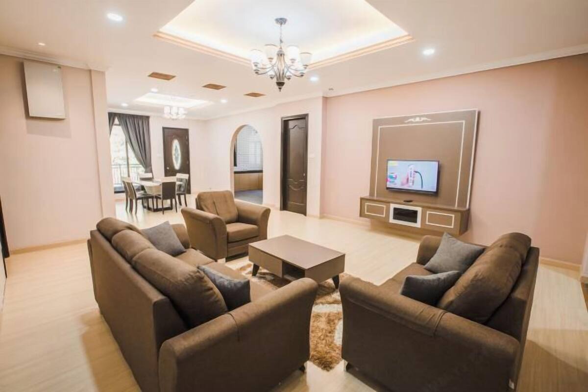 A modern living room with sofas, a coffee table, a TV, and a chandelier.