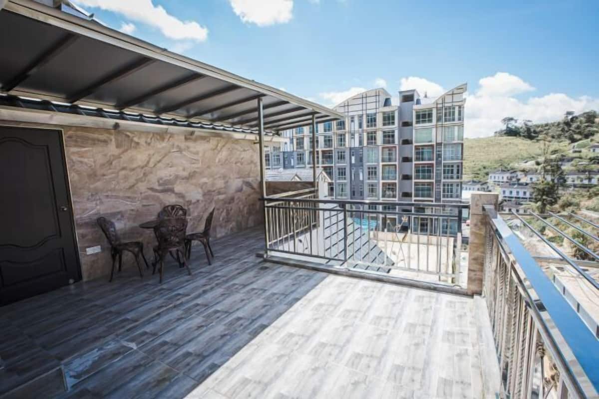 A balcony with a stone wall, a door, and a table with chairs.