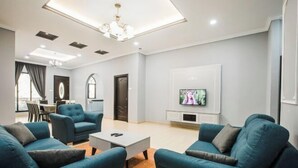 Una sala de estar moderna con un juego de sofá, una mesa de centro, un televisor y un comedor con sillas y una mesa.