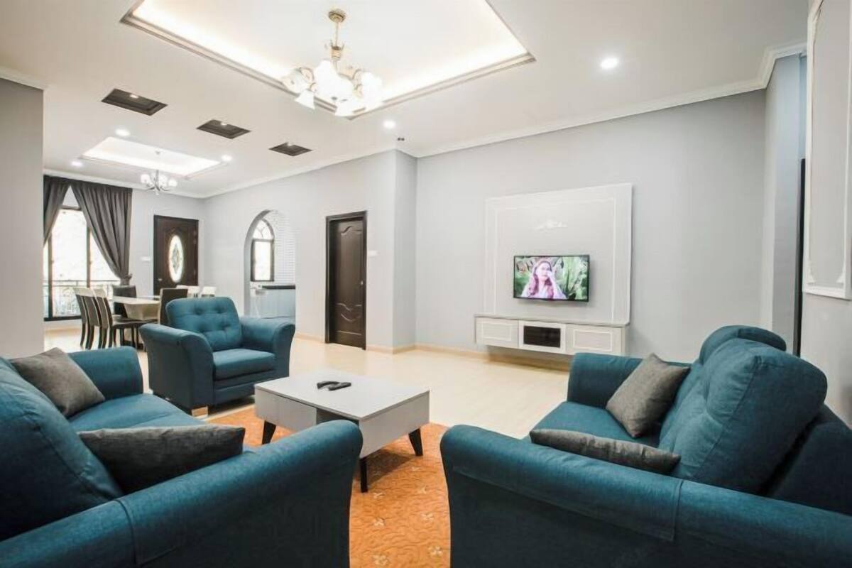 A modern living room with a sofa set, a coffee table, a TV, and a dining area with chairs and a table.