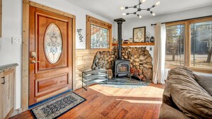 A cozy living room with a wooden door, a stone fireplace, a sofa, and a chandelier. - Pine Lantern Retreat (South Lake Tahoe)