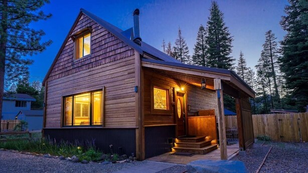 A wooden cabin with a porch, a chimney, and a window with blinds. - Pine Lantern Retreat (South Lake Tahoe)