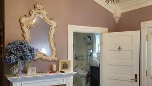 Une pièce avec une cheminée, un miroir et une porte donnant sur une salle de bain.
