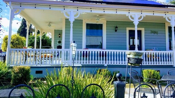 Une maison à deux étages avec un porche et un petit jardin à l’avant.