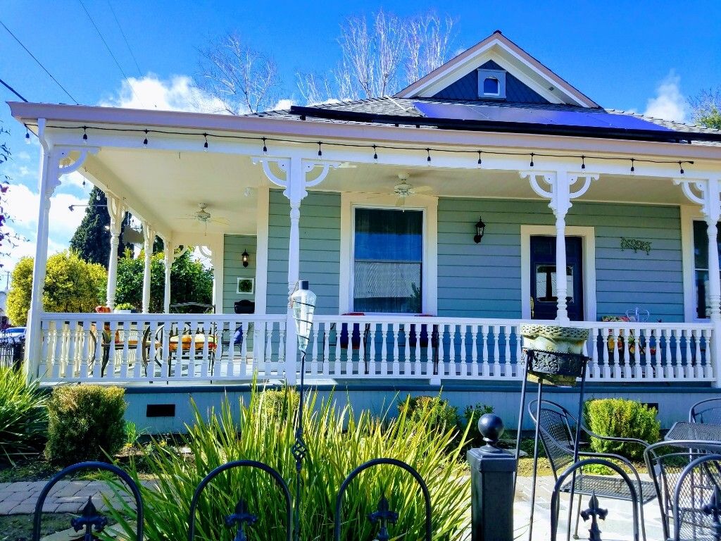 A two-story house with a covered porch and a small garden area in front.