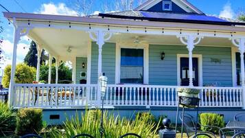 A two-story house with a covered porch and a small garden area in front.