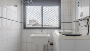 Ein kleines Badezimmer mit einem Waschbecken, einem Fenster mit Gitterrost und einer Duschkabine.