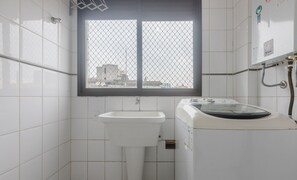 A small bathroom with a sink, a window with a metal grid, and a shower area. - Apartment 200m From Beira-mar Norte Rmi1101 (Florianópolis)