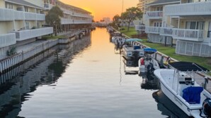 A canal lined with boats and buildings with balconies, reflecting the sunset. - Sandpiper Cove 8249 Studio In Destin, FL  2-minute walk to the beach! (Destin)