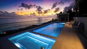 A pool area with a sunset view, a lifeguard chair, and a lounge area with chairs. - SeaDreams 1: Ocean Condos w/Pool. Jacuzzi & Rooftop Patio; Stay a Week, Save 20% (West Bay)