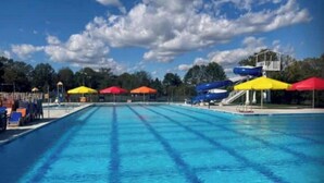 Une piscine dotée de plusieurs couloirs de nage, de toboggans et de parasols colorés.