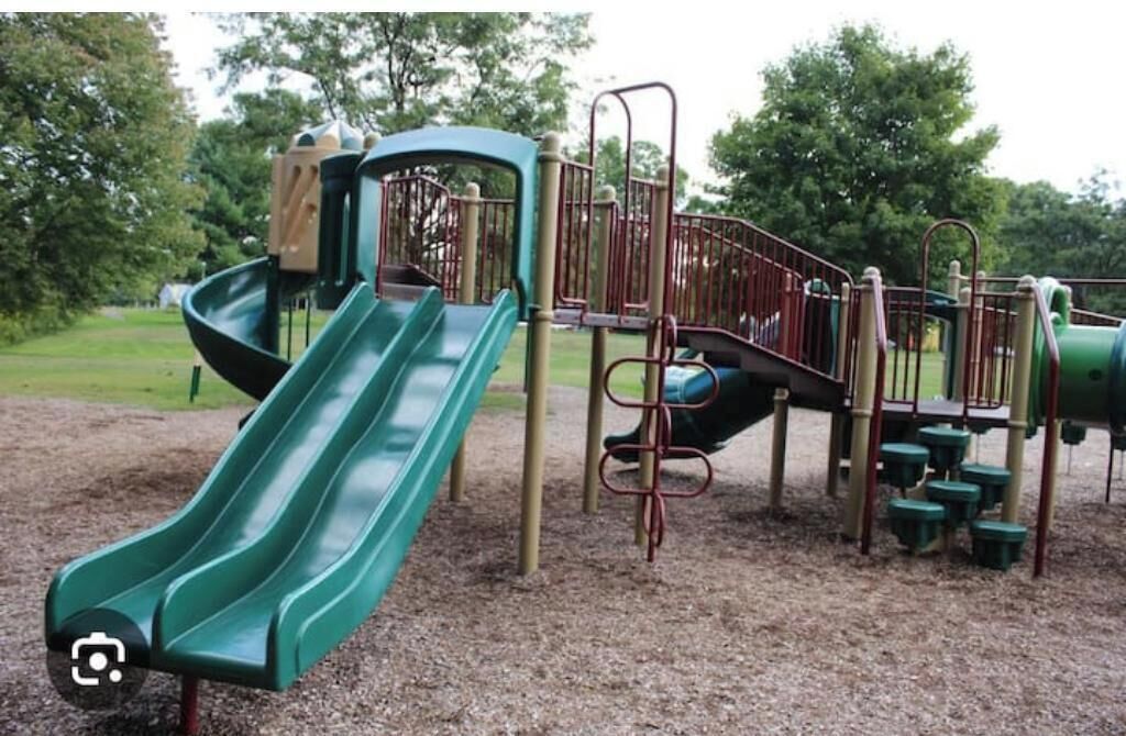 Un parque infantil con dos toboganes verdes y una estructura para escalar.