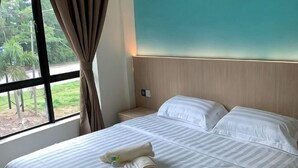 A hotel room with a bed, a nightstand, a window with curtains, and a view of greenery outside. - M Quality Hotel (Galas)