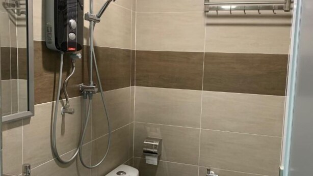 A bathroom with a toilet, a shower, and a towel rack. - M Quality Hotel (Galas)
