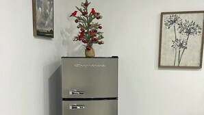 A modern kitchen with a stainless steel refrigerator, a vase with red and silver ornaments, and two framed artworks on the walls. - Lovely and private studio centrally located. (Miami)