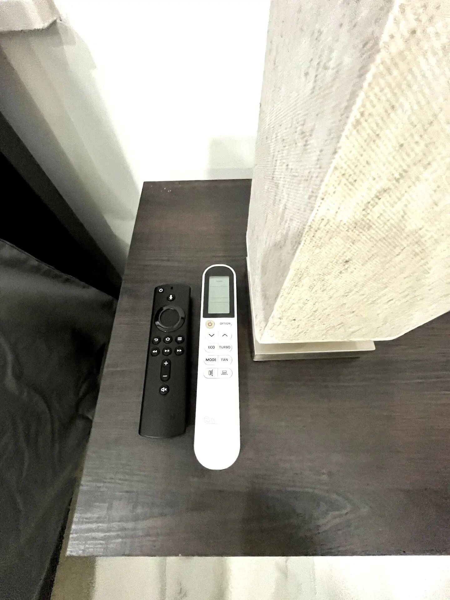 Un control remoto y un dispositivo electrónico blanco sobre una superficie de madera oscura.