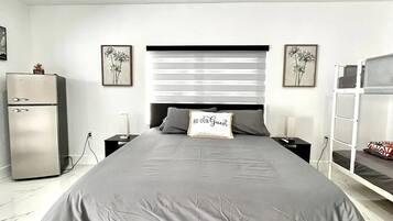A modern bedroom with a large bed, bedside tables, a wardrobe, and a bunk bed.