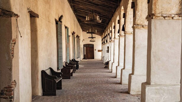 A corridor with benches along the walls, a brick floor, and a wooden ceiling. - Symphony Suite (Paso Robles)