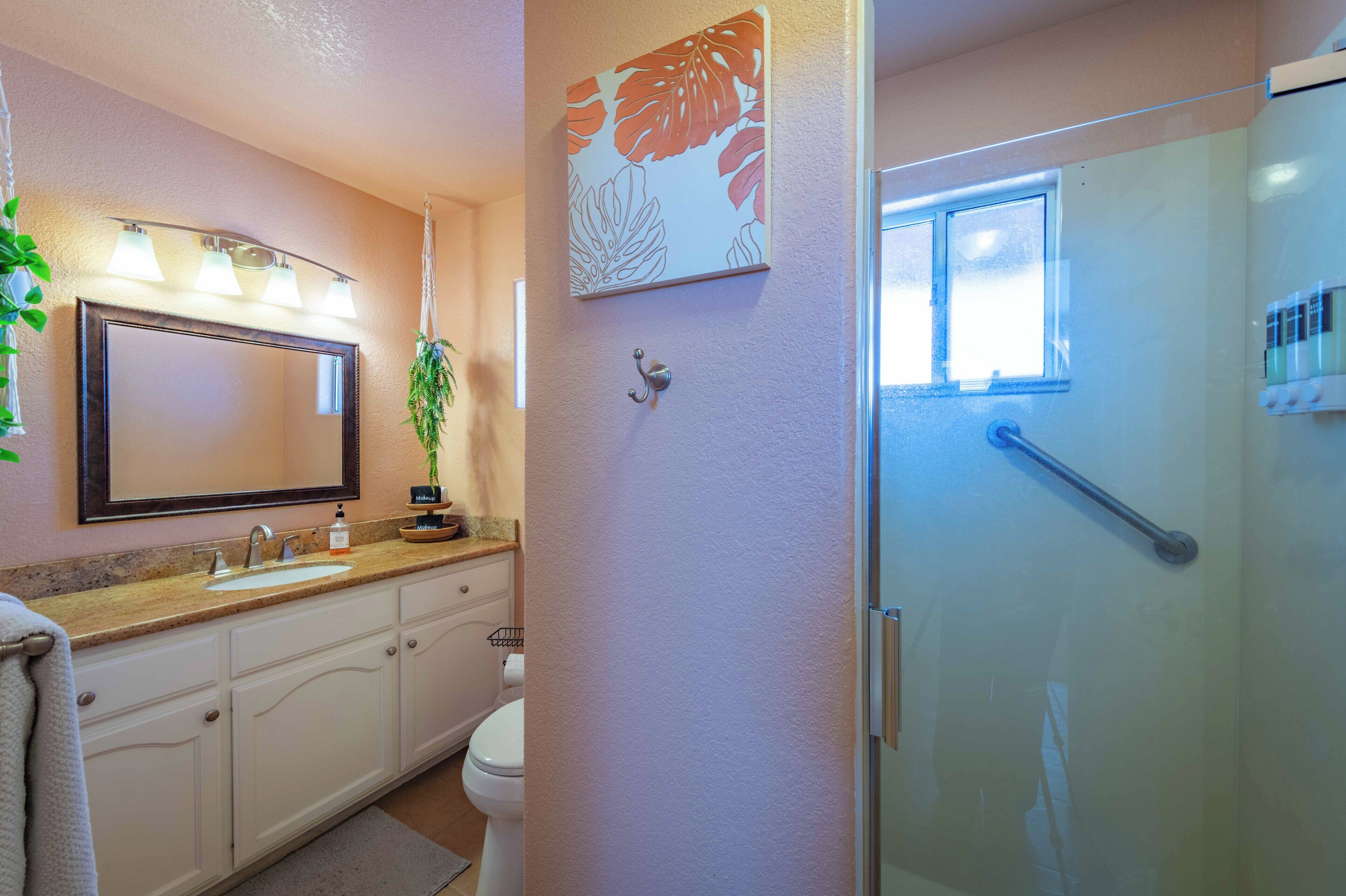 A bathroom with a large mirror, a sink, a toilet, and a shower area.