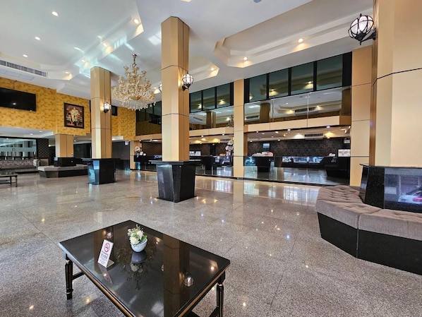 A spacious lobby with a reception desk, seating areas, and a chandelier. - Boutique Bravo Hotel (Pattaya)