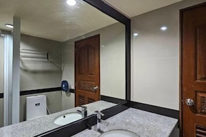 A bathroom with a sink, mirror, and wooden door. - Boutique Bravo Hotel (Pattaya)