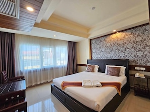 A hotel room with a large bed, a desk, and a chair. - Boutique Bravo Hotel (Pattaya)