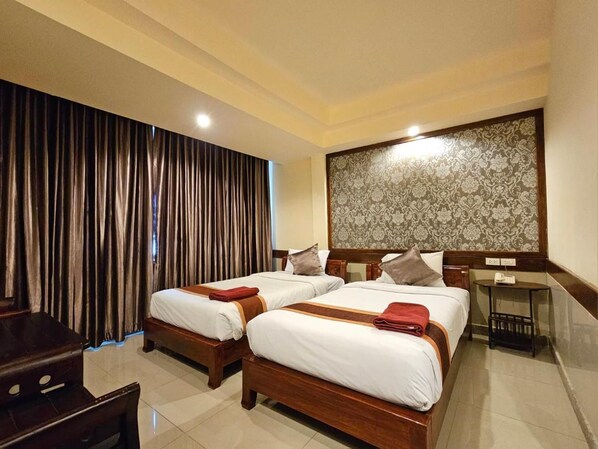 A hotel room with two wooden beds, a desk, and a large window with curtains. - Boutique Bravo Hotel (Pattaya)