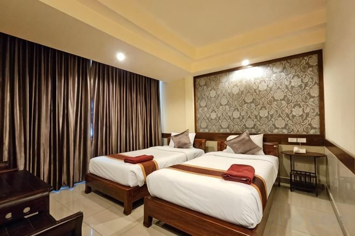 A hotel room with two beds, a desk, and a nightstand.