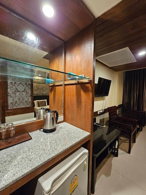 Un espace de vie compact comprenant une kitchenette, un coin repas et un téléviseur.