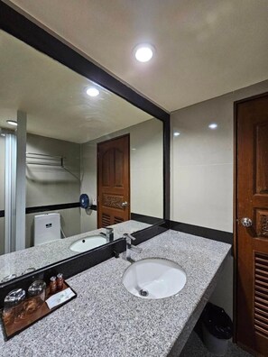 A bathroom with a large mirror, a sink, and a door. - Boutique Bravo Hotel (Pattaya)