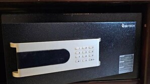 Una cassaforte nera con tastierino numerico e un logo nell'angolo in alto a destra.