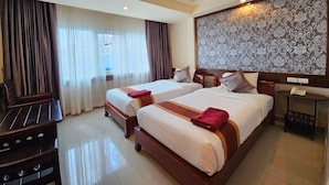 A hotel room with two beds, a desk, and a large patterned wall. - Boutique Bravo Hotel (Pattaya)