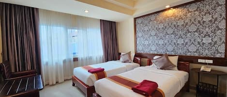 A hotel room with two beds, a desk, and a large patterned wall.
