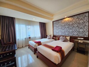 A hotel room with two beds, a desk, and a large patterned wall. - Boutique Bravo Hotel (Pattaya)