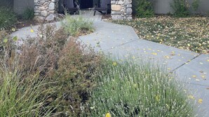 Una casa con fachada de piedra, techo oscuro y un porche con dos sillas.