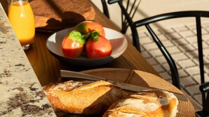 Une table avec du pain, des tomates et un verre de jus d’orange.