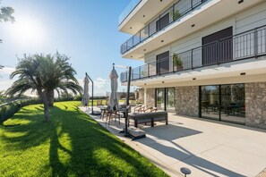 Un bâtiment moderne à plusieurs étages doté d’un patio aménagé avec du mobilier d’extérieur et un palmier.