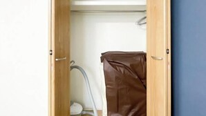 Un armario con puerta de madera, un aspirador y una bolsa marrón.