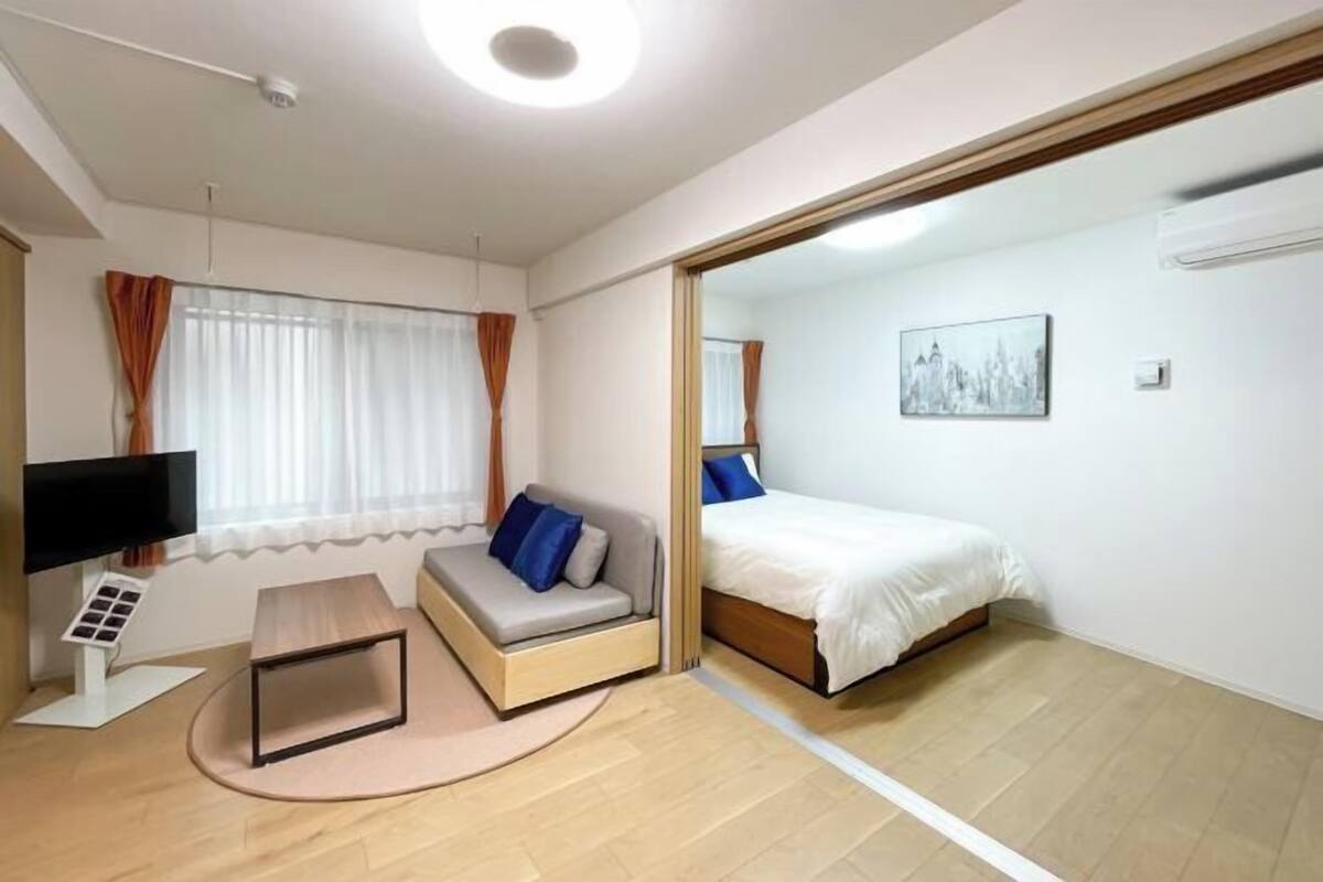 Una stanza moderna con un letto, un divano, una TV e un piccolo tavolino.